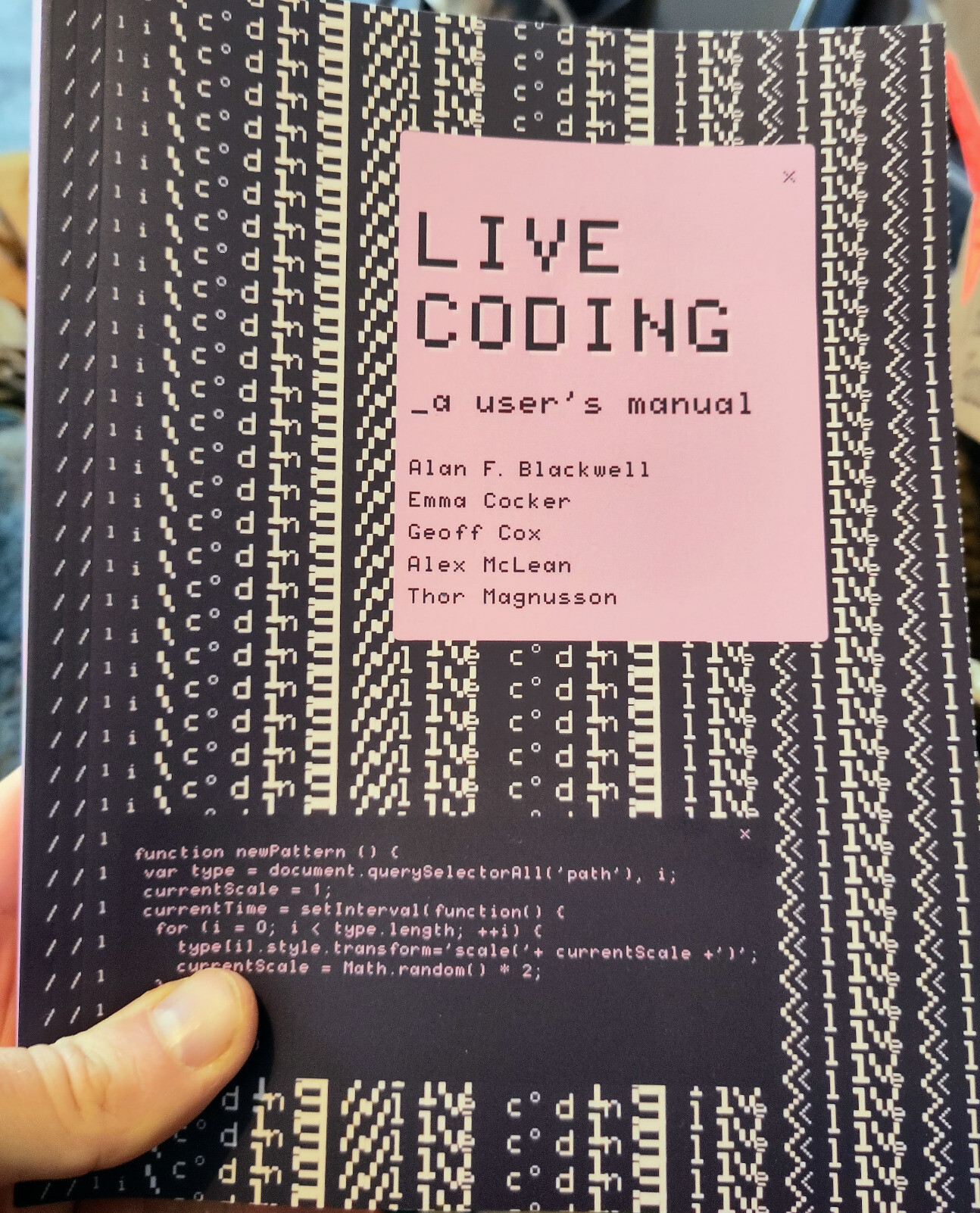 Book cover for LIVE CODING: a user's manual, by Alan F. Blackwell, Emma Cocker, Geoff Cox, Alex McLean and Thor Magnusson With text 'live coding' in the background manipulated into a repeating pattern. The code for generating this pattern is also shown in __a box, partially obscured by my thumb, saying something like: function newPattern () { var type = document.querySelectorAll('path'), i; currentScale = 1; currentTime = setInterval( function() { for (i = 0; i < type.length; ++i) ( __type[i].style.transform='scale('+ currentScale +)'; currentScale = Math.random() * 2; } }